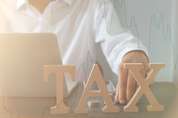 Tax, investment, business planning, and economic stock chart concept with businessman using laptop and stacking coins, symbolizing financial strategy and tax management