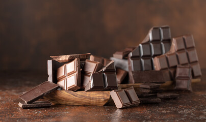 Broken bitter and milk chocolate bars on a brown background.