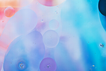 Close-up of the movement of oil droplets on the water surface. Colorful abstract macro background of oil drops on the water surface.