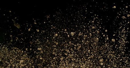Detailed wave of airborne clay dust swirling in chaotic motion, captured in freeze  motion. Dramatic natural explosion of earthy particles on black background.