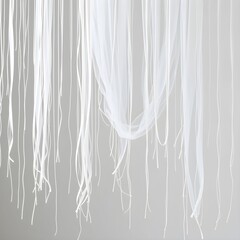 Delicate white fabric strands cascade downwards, creating a flowing, ethereal pattern against a neutral backdrop.