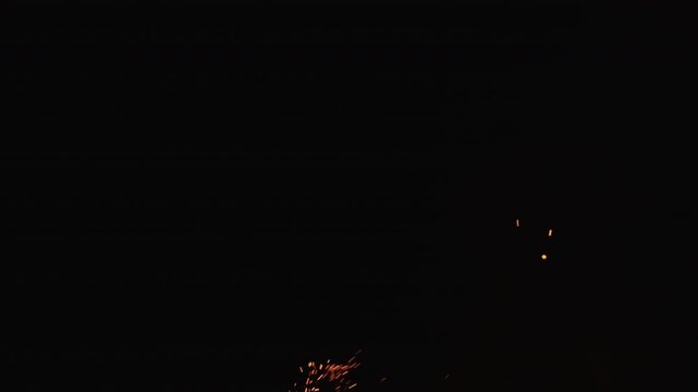 Slow motion of sparks and embers from campfire flying over black background