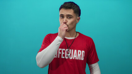 Young hispanic lifeguard man playfully sends a kiss while wearing a red shirt against an isolated...