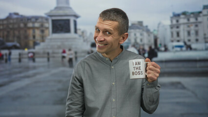 Man holding coffee cup with message in urban outdoor setting at trafalgar square smiling...