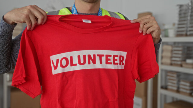 Man shirt holds warehouse box while young hispanic volunteer arranges donation charity tee. - Powered by Adobe