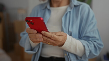 Woman using smartphone in living room, showcasing middle age lifestyle in new home setting, with focus on hands and modern technology.