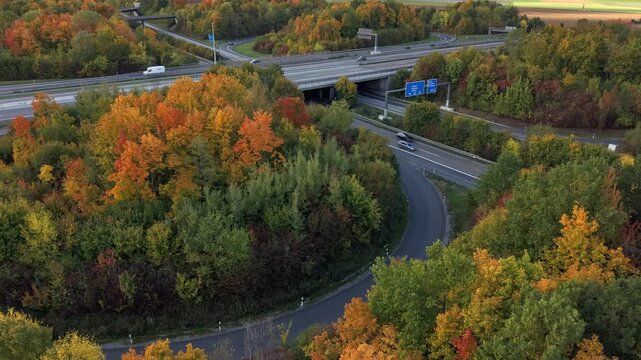 Timelaps of the highway intersection at dawn between the vibrant autumn trees