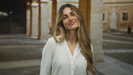 Fototapeta premium Woman crosses bare arms in university courtyard; confidence determination.