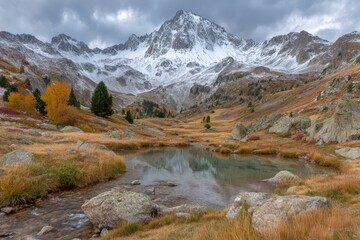 Expansive mountain landscape showcasing autumn foliage and tranquil lake reflecting snow-capped peaks under dramatic cloud formations creating an enchanting natural setting