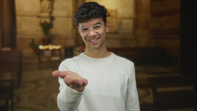 Man offers open palm gesture in church building aisle lit by soft candlelight and stone walls framing altar; invitation. - Powered by Adobe