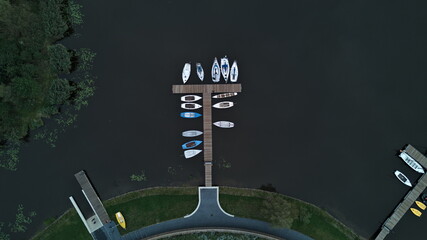 Aerial view of wooden pier with boats docked on calm lake surface