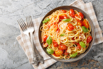 Italian Spaghetti Margherita with tomatoes, mozzarella cheese, basil, garlic and olive oil close-up in a plate on the table. Horizontal top view from above