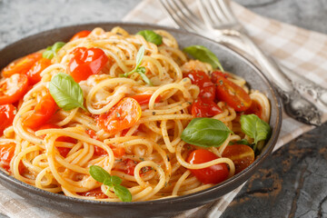 Margherita Spaghetti with cherry tomatoes, olive oil, butter, garlic, fresh basil, creamy mozzarella tossed closeup on the plate on the table. horizontal