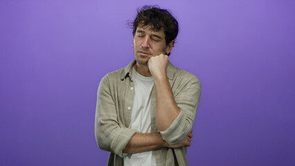 Obraz premium Handsome hispanic man with eyes closed and hand on chin against purple background expressing contemplation and relaxation in casual attire