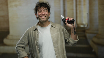 Hispanic man holding screwdriver in front of roman-style columns on a university campus, exuding...