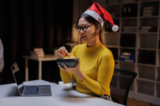 Happy asian woman typing an email on laptop video calling on Christmas at home.enjoy christmas eve weekend xmas celebrate festive seasonal moment.