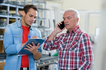 businessman on the phone with worker with clipboard