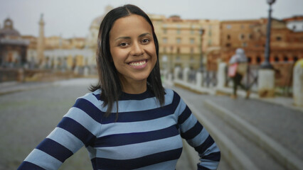 Hispanic woman smiling in striped shirt at roman ruins outdoors with blurred historic architecture...