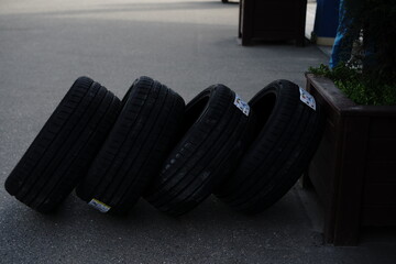 Four black tires resting against a planter on a city street in the late afternoon sun