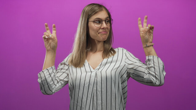 Blonde woman showing air quotes gesture with both hands in a studio with bright magenta background; sarcasm.