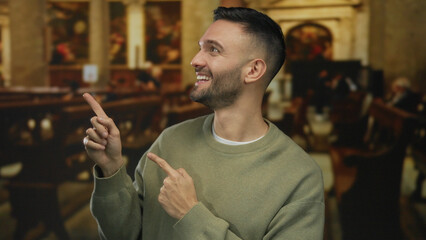 Young man smiling and pointing indoors in a church setting conveying faith and positive emotion through a serene and contemplative atmosphere.