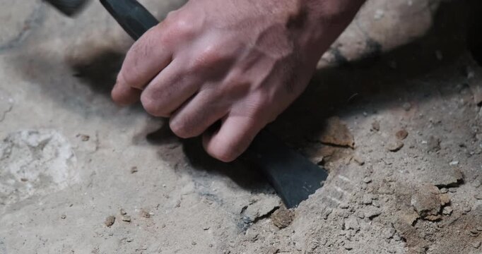 Dynamic close-up with motion blur of a craftsman striking stone with a hammer and chisel. Dust and particles fly on impact. Historical stonemasonry in action.