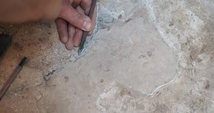 Close-up of a craftsman's hand meticulously following a line on stone with a chisel. (Sound On) Features clear, rhythmic tapping sounds (ASMR). Historical artifact restoration or precision stonework.
