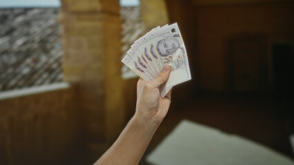 Hand holding singapore dollars indoors at a university with an old architectural background,...