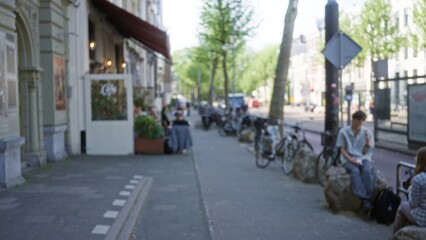 Blurred street scene in amsterdam showing people outdoors with bicycles and cafe showing a relaxed urban lifestyle.