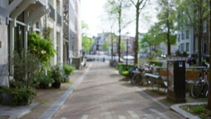 Blurred street scene in a european city with bicycles and trees lining a canal showcasing an outdoor urban landscape in daylight with defocused background showcasing serenity.