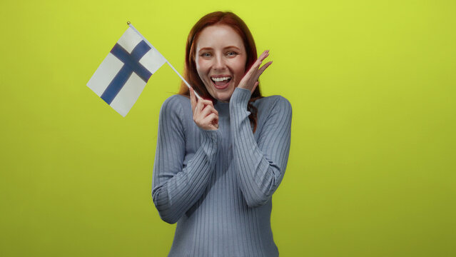 Woman holding finnish flag cheerfully against vibrant yellow background, embodying national pride and joyful expression.