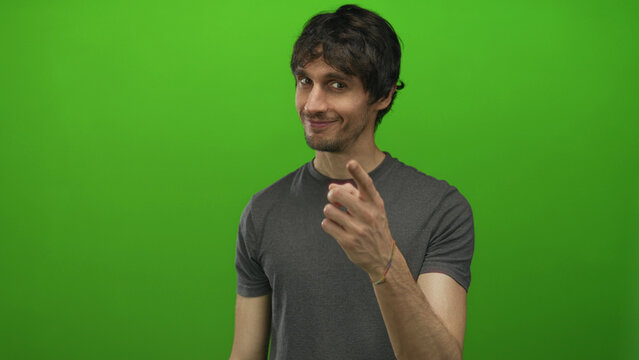 Man with finger pointing to camera in studio green set as he smiles and leans slightly forward; confidence.