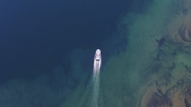 The craft speeds across turquoise water, leaving a white trail over the bright rocky bed that shows through perfectly clear Lake Lama. Stable topdown track brings out detail for tourism, mapping and e