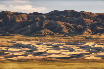 A stunning desert landscape showcasing rolling dunes against rugged mountains