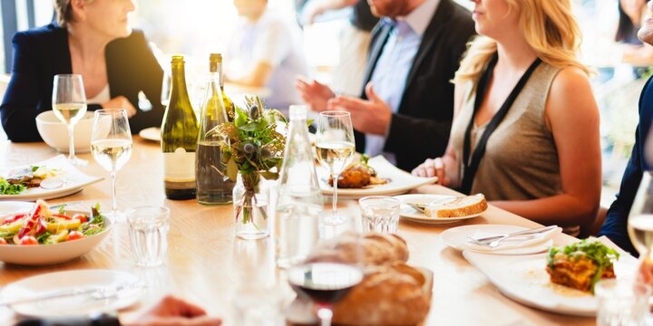 Group dining at a restaurant, enjoying a meal with wine. People socializing, sharing food, and dining together. Restaurant ambiance with wine and food. Group of people dining at restaurant. - Powered by Adobe