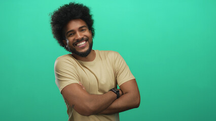 Smiling african american man crossing arms confidently against a vibrant green background,...