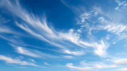 Wispy cirrus clouds streak across a clear blue sky.
