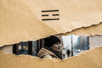 A vintage black-and-white photograph of a man in a trench coat and fedora, placed on a torn document