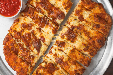 Cheesy breadsticks served with a side of marinara sauce.