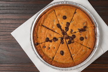 Chocolate chip cookie dessert baked in a round tin and cut into slices.