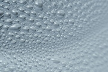 This close-up image reveals an intricate surface covered with countless water droplets.