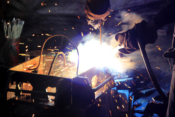 Industrial Welding Process with Bright Sparks and Blue Flame