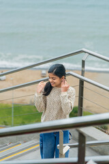 A teen is standing on a metal staircase overlooking the ocean