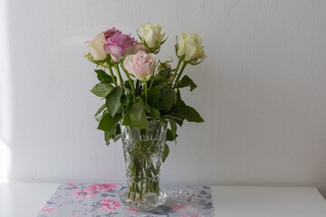 Pastel colored roses in a vase on a table