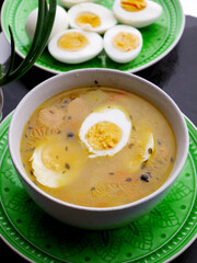 A bowl of autumn soup with two halves of a hard-boiled egg in it. A separate plate holds more sliced hard-boiled eggs.