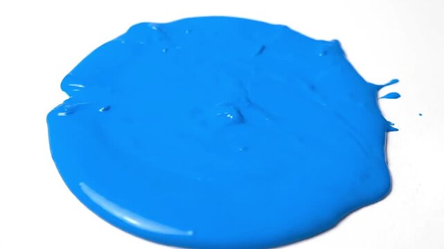 Vibrant blue paint splattered on a white background creating an abstract shape.