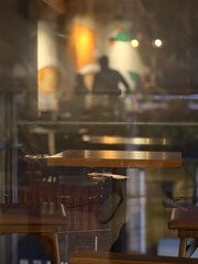 interior of a restaurant, warm cafe interior viewed through glass with soft reflections and cozy lighting, creating a relaxed evening atmosphere. Perfect for lifestyle, hospitality, and interior desig