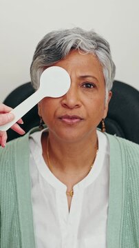 Face, old woman and vision in clinic, eye test and reading assessment, hand and health consultation. Check, eyesight and elderly patient with optometry exam, senior person and healthcare in hospital