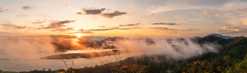 Obraz premium A brilliant panoramic sunrise from Phu Pha Dak, Nong Khai, Thailand. The sun's rays create a stunning glow on the mist covering the vast Mekong River valley below.