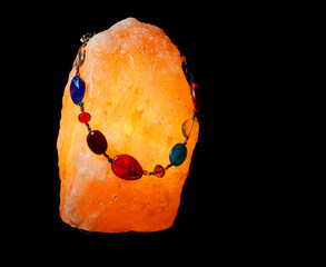 Multi-coloured beaded necklace displayed on a Himalayan salt lamp
